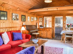 a living room with a red couch and a piano at The Cottage At Dockens Water in Fritham +18 photos