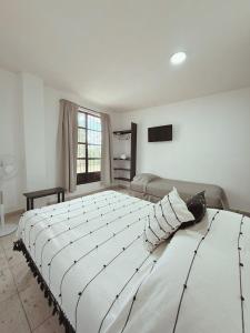 a large white bed in a room with a couch at Casa Monarca in Oaxaca City