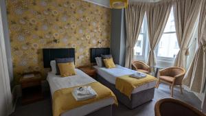 a hotel room with two beds and a window at Alexandra Hotel in Eastbourne