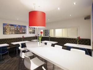 Un comedor con una gran mesa blanca y sillas. en ibis Styles Amsterdam Central Station, en Ámsterdam