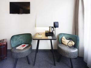 Habitación con 2 sillas y mesa con teléfono. en ibis Styles Amsterdam Central Station, en Ámsterdam 38 fotos más