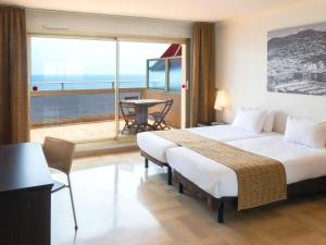 a bedroom with a bed and a balcony with a table at Aparthotel Adagio Nice Promenade des Anglais in Nice