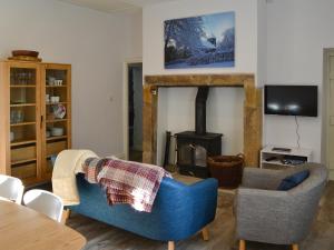 een woonkamer met 2 blauwe stoelen en een open haard bij Horsley Cottage in Rochester