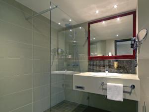 a bathroom with two sinks and a glass shower at Mercure Hotel Dortmund Messe in Dortmund +73 photos