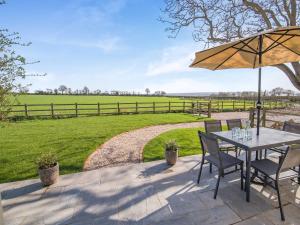 a patio with a table and chairs and an umbrella at Stone Cottage in Wedmore