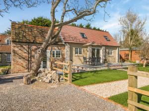 a house with a tree and a fence at Stone Cottage in Wedmore
