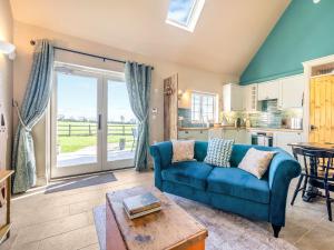 a living room with a blue couch and a kitchen at Stone Cottage in Wedmore