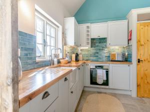 a kitchen with white cabinets and a sink at Stone Cottage in Wedmore +13 photos