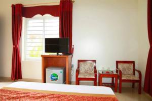 Un dormitorio con una cama y dos sillas y un televisor. en Khách Sạn Đại An, 