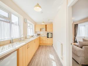 - une cuisine avec des placards en bois, un évier et un canapé dans l'établissement Macey's Cottage - Uk42146, à North Somercotes
