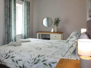 a bedroom with a bed and a table with a mirror at Sunrise Cottage - Uk35813 in Llanddulas