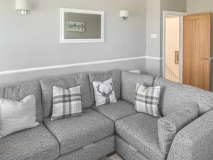 a living room with a gray couch with pillows at Sunrise Cottage - Uk35813 in Llanddulas