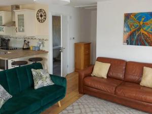 a living room with a couch and a kitchen at Wild Lupin in Kessingland