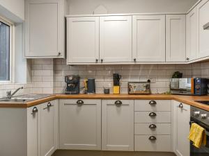 Una cocina con gabinetes blancos y encimera. en Grey Gull, en Whitby