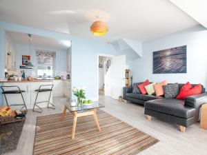 a living room with a black couch and a table at Seaspray, Coastguard Cottages in Dawlish