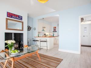 a living room with a glass table and a kitchen at Seaspray, Coastguard Cottages in Dawlish