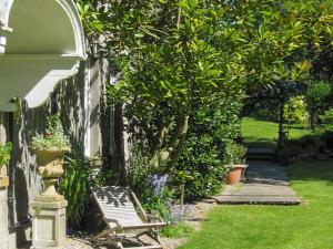a bench sitting in the grass next to a tree at Bailiffs House - Uk48744 in Llandybie