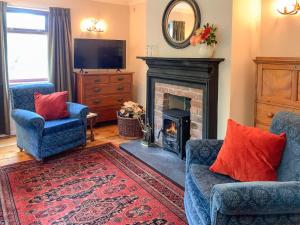 un soggiorno con due sedie e un camino di Forester's Cottage a Kildary
