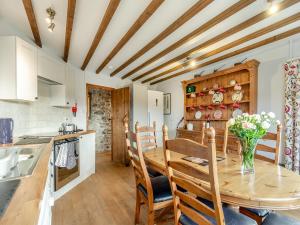a kitchen and dining room with a wooden table and chairs at Cwm Eithin Cerbid - Cottage in Llanhowell