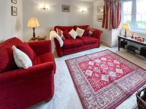 a living room with two red couches and a rug at Green Trees in Maidstone
