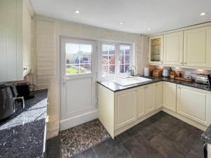 a kitchen with white cabinets and a white door at Green Trees in Maidstone