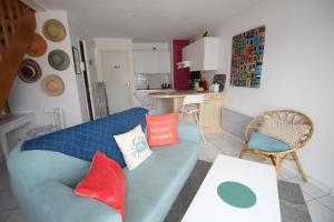 a living room with a blue couch and a kitchen at TY SEA in Crozon