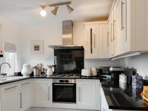 a kitchen with white cabinets and a stove top oven at Wattle Cottage in Belper