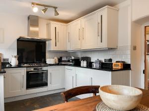 a kitchen with white cabinets and a wooden table at Wattle Cottage in Belper