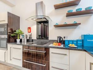a kitchen with white cabinets and blue counter tops at Ty Menyn - Uk45716 in Brynteg +8 photos