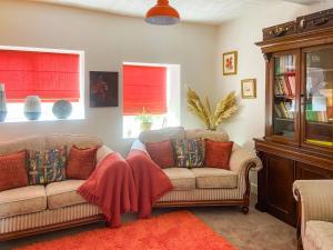a living room with two couches and two windows at Ddwylig Isaf Farmhouse - Uk48624 in St Asaph