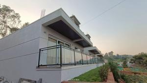 a white house with large windows on the side of it at Mountain Berries Resort in Panchgani +6 photos