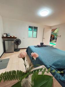 a bedroom with a bed with a blue blanket and flowers at Kama Siri Koh Kood in Ko Kood