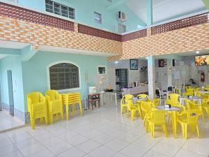 un restaurant avec des chaises et des tables jaunes dans une pièce dans l'établissement Pousada Boa Vista, à Cachoeira Paulista