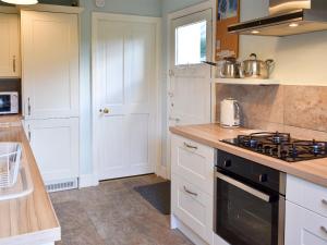 a kitchen with white cabinets and a stove top oven at Hey Down in Keswick