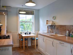 a kitchen with a sink and a table and a window at Hey Down in Keswick