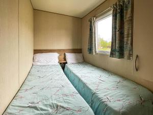 two beds in a small room with a window at Au Bords Du Lac - Uk49028 in Tattershall +2 photos