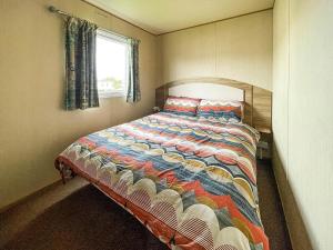 a bedroom with a bed with a colorful quilt at Au Bords Du Lac - Uk49028 in Tattershall