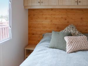 un letto con testiera in legno e 2 cuscini di The Lodge - Uk48785 a Llangefni