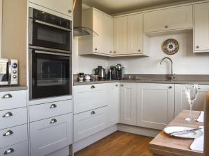 Una cocina con gabinetes blancos y electrodomésticos negros. en The Wolfs Den - Uk49083, en Winewall
