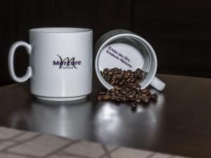 Dos tazas de café junto a una pila de granos de café en Mercure Frankfurt City Messe, en Frankfurt