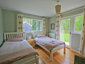 zwei Betten in einem Zimmer mit zwei Fenstern in der Unterkunft Still Waters in Wroxham