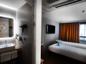 a bathroom with a bed and a sink and a mirror at ibis Styles Clermont-Ferrand Aéroport in Clermont-Ferrand