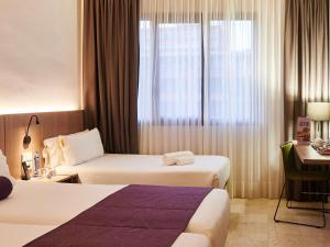 a hotel room with two beds and a desk and a window at Mercure Barcelona Condor in Barcelona