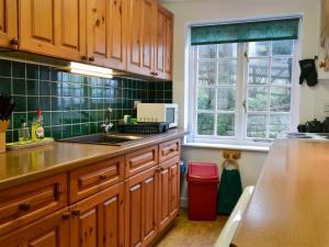 a kitchen with wooden cabinets and a sink at White Rose Cottage in Robin Hood's Bay