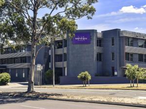 a building with a purple sign on the side of it at Mercure North Melbourne in Melbourne