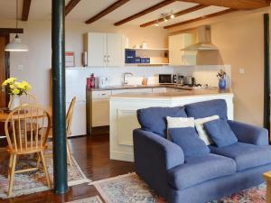 a living room with a blue couch and a kitchen at Jasmine Cottage - E1493 in Scalby