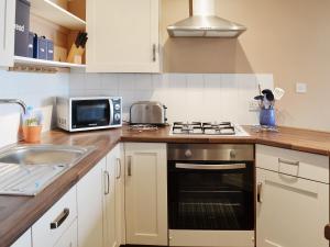 a kitchen with a sink and a stove top oven at Jasmine Cottage - E1493 in Scalby
