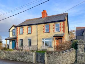 a yellow house with a stone fence in front of it at Bryn View Villa - Uk48825 in Mochdre