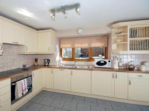 Una cocina con gabinetes blancos y un fregadero. en Cerniw - Cottage, en Aberaeron
