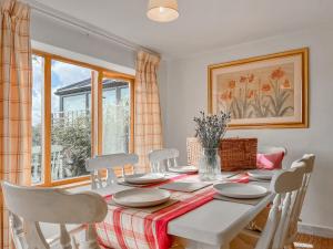 a dining room with a white table and chairs at Drovers Cottage in Tetbury